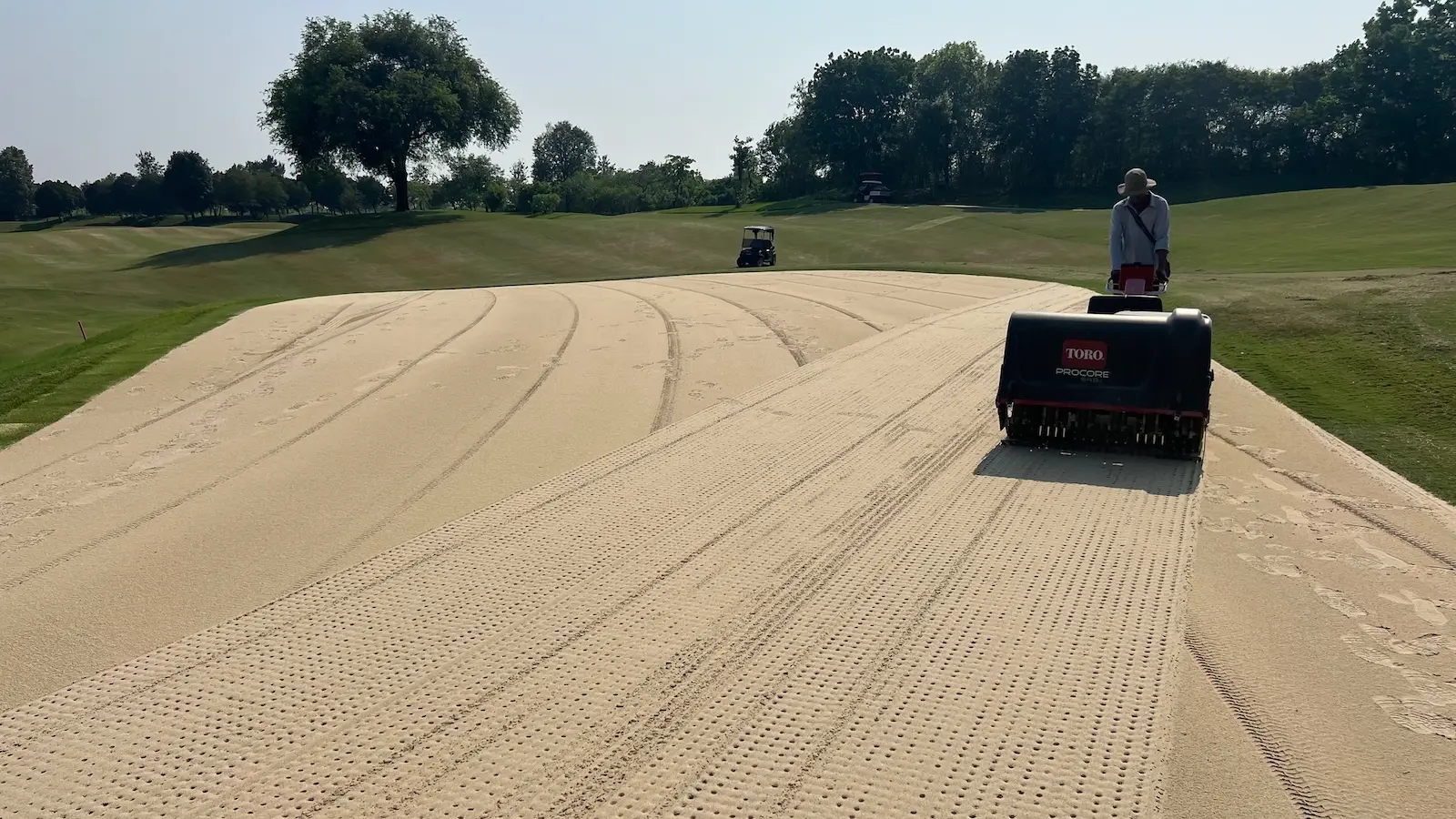 Aerating golf course greens after topdressing